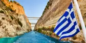 Corinth channel with Greek flag blowing in wind on ship in Greece
