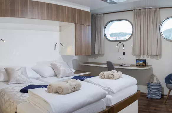 Twin bedroom with porthole window view aboard the Ms II Mare ship