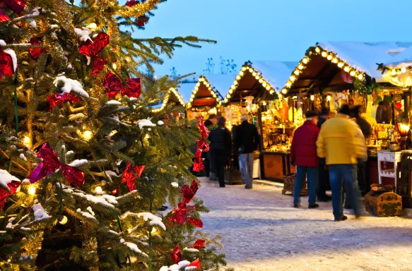 Christmas Market covered in snow with customers shopping at lit up stalls