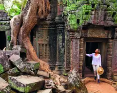 A Woman paused in the doorway of an ancient ruin of Ta Prohm, looking in up in admiration.