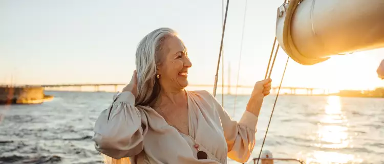 Senior woman adjusting her hair and enjoying sunset on private yacht